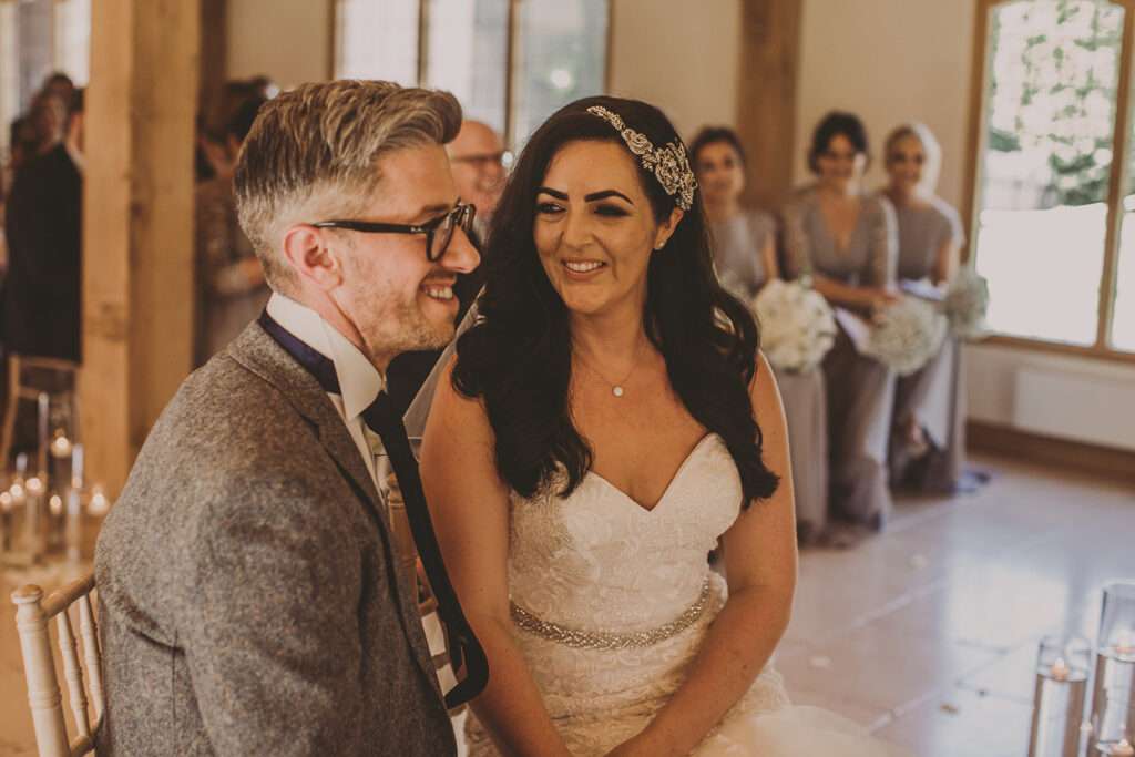bride and groom sit together holding hands during wedding ceremony