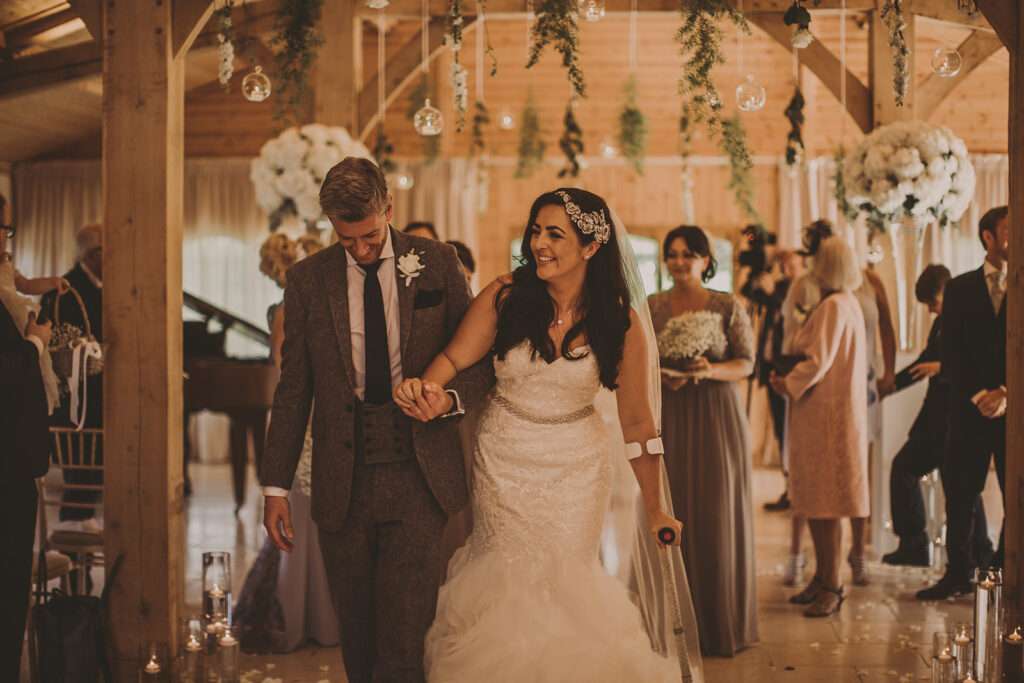 bride and groom walk up the aisle hand in hand after their Colshaw Hall wedding