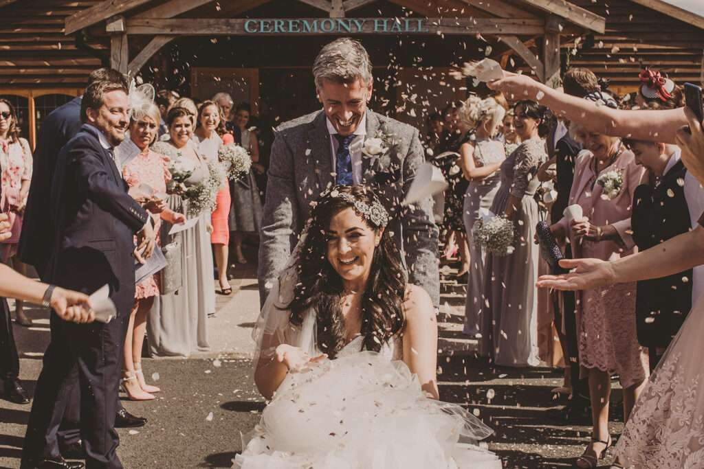 bride and groom leave Colshaw Hall whilst guests throw confetti
