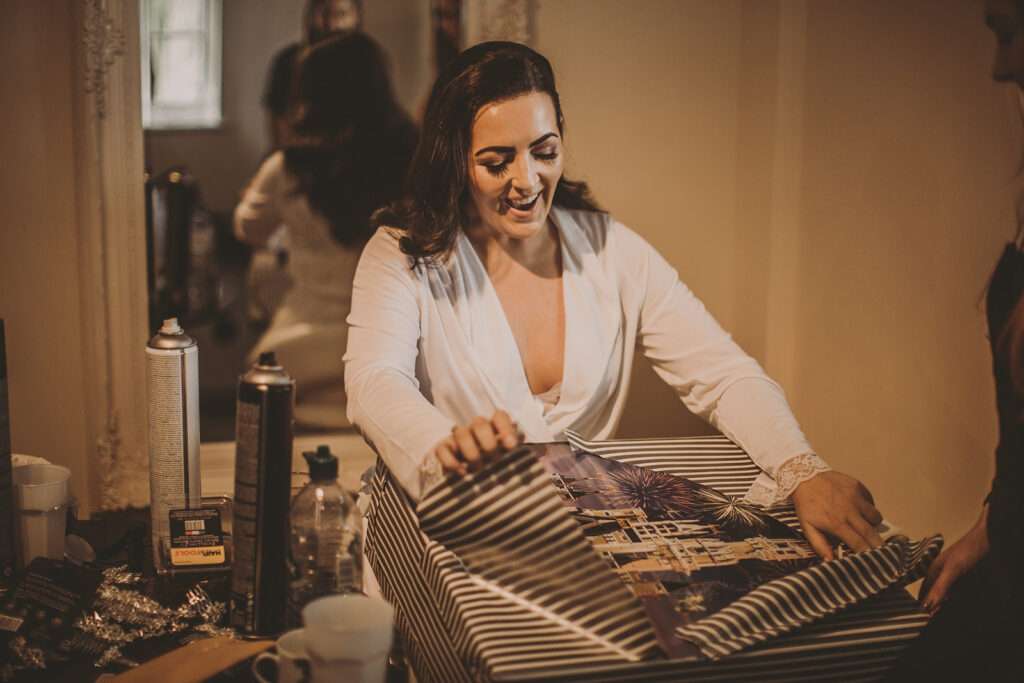 bride opening gift during bridal preparations at Colshaw Hall