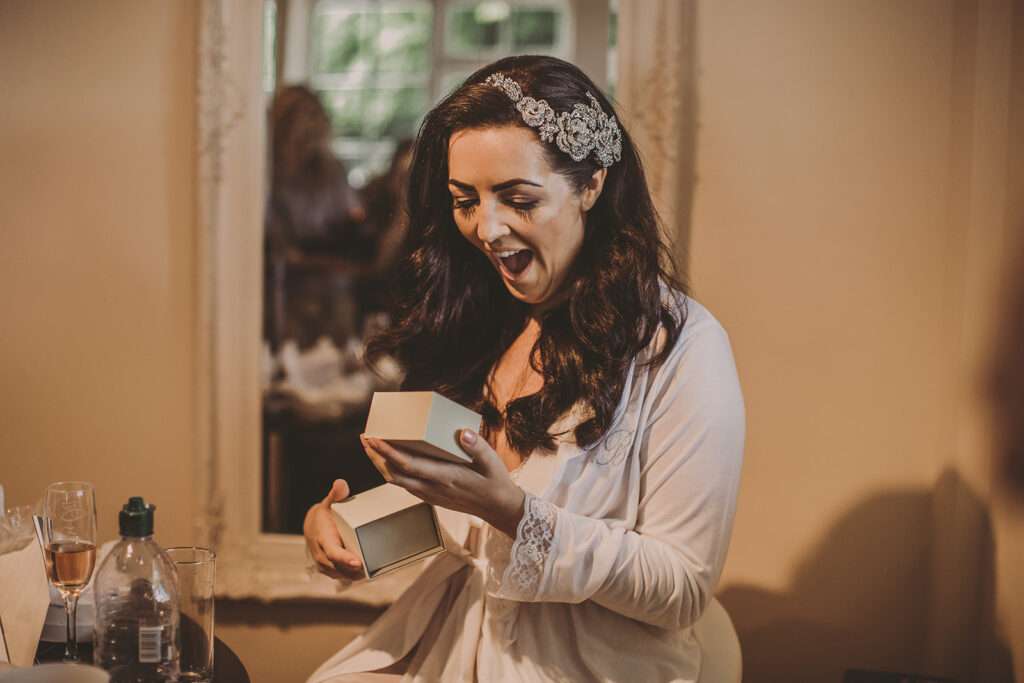 bride opens a gift during bridal preparations at Colshaw Hall