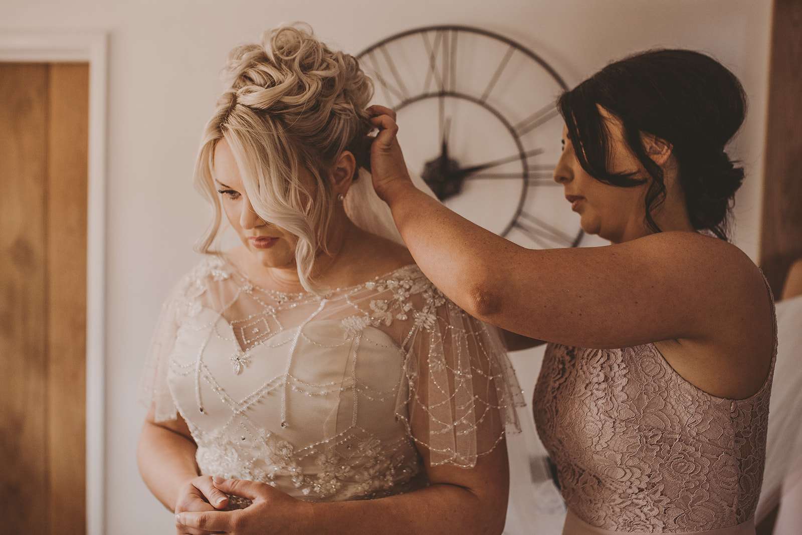 bridesmaid adjusts brides hair during bridal preparations at Osmaston Hall