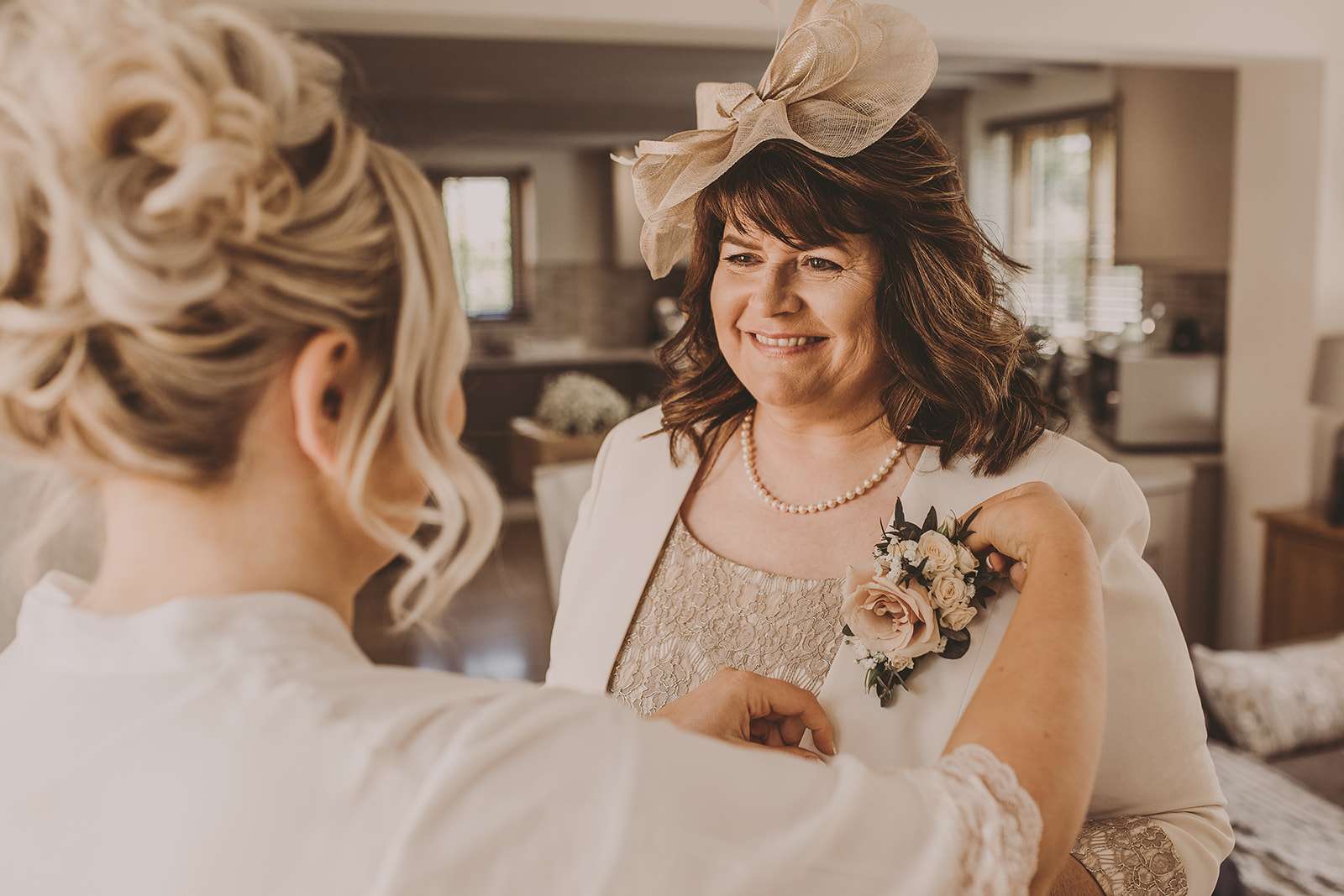 bride help attaching floral button hole to her mums dress