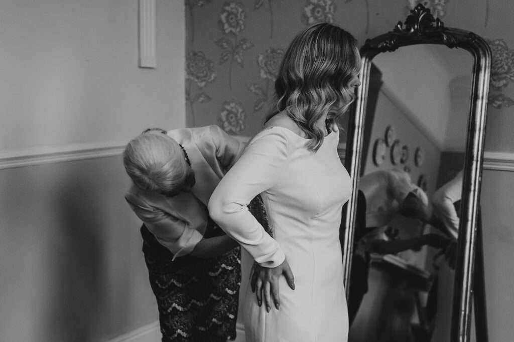 bride being helped into her wedding dress