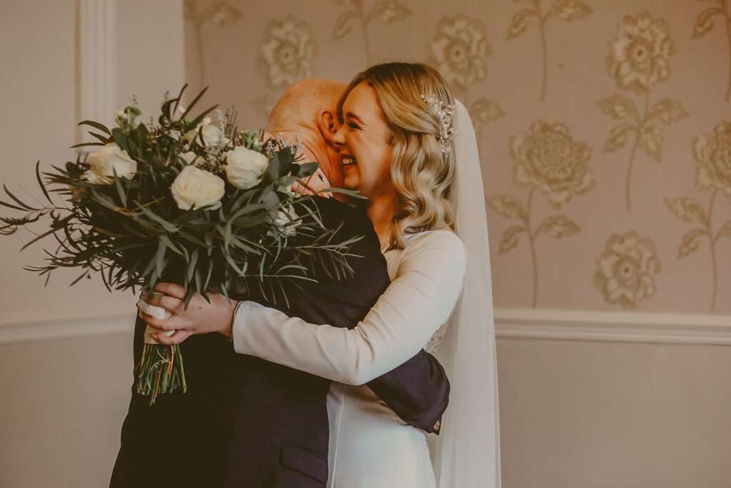 bride hugs dad after he sees her in her wedding dress