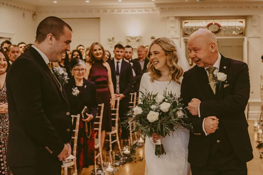 bride and her day arrive at the end of the aisle to meet groom