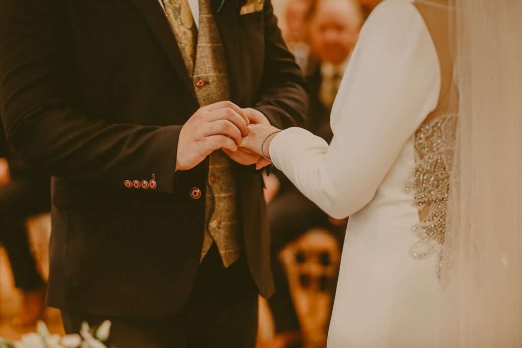 groom placing the ring on brides finger during wedding ceremony