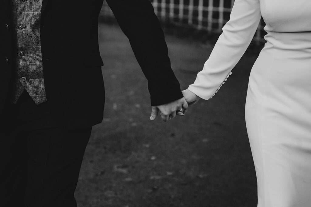 black and white photo of bride and groom holding hands