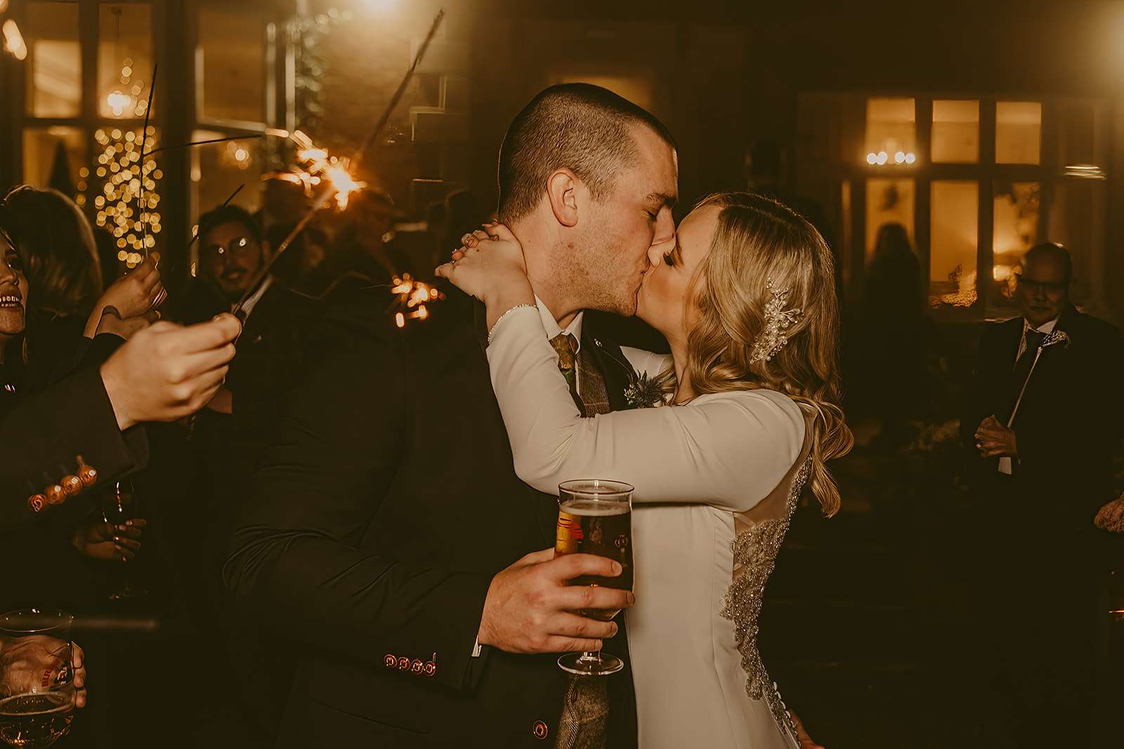 bride and groom kiss during evening reception sparklers